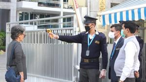 A security personnel uses a thermal screening device on visitors at the entry gate of a housing society in Gurugram, on Sunday, as a precautionary measure to check the spread of coronavirus.(Yogendra Kumar/HT Photo) A security personnel uses a thermal screening device on visitors at the entry gate of a housing society in Gurugram, on Sunday, as a precautionary measure to check the spread of coronavirus.(Yogendra Kumar/HT Photo)