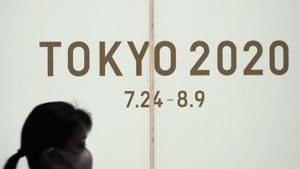 A woman walks past a large display promoting the Tokyo 2020 Olympics in Tokyo.(AP)