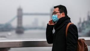 Covid 19: A commuter, wearing a protective face mask, crosses London Bridge in view of Tower Bridge in London, UK.(Bloomberg) Covid 19: A commuter, wearing a protective face mask, crosses London Bridge in view of Tower Bridge in London, UK.(Bloomberg)