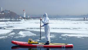 A sup surfer wearing a protective suit as a show of support for the people fighting against the spread of coronavirus disease (COVID-19) takes part at an annual A sup surfer wearing a protective suit as a show of support for the people fighting against the spread of coronavirus disease (COVID-19) takes part at an annual