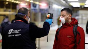 A security staff member checks the temperature of a passenger arriving from Turin and Milan by train, at Naples Central station in Italy on March 22.(Reuters Photo) A security staff member checks the temperature of a passenger arriving from Turin and Milan by train, at Naples Central station in Italy on March 22.(Reuters Photo)