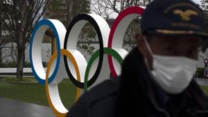 A security guard walks past the Olympic rings near the New National Stadium in Tokyo, Monday, March 23, 2020. T(AP) A security guard walks past the Olympic rings near the New National Stadium in Tokyo, Monday, March 23, 2020. T(AP)