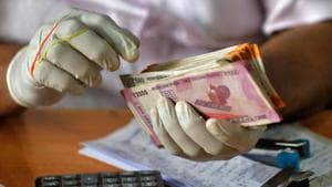 A trader wearing protective hand gloves counts currency notes at a market during a 21-day nationwide lockdown to limit the spreading of coronavirus disease (COVID-19), in Kochi.(REUTERS) A trader wearing protective hand gloves counts currency notes at a market during a 21-day nationwide lockdown to limit the spreading of coronavirus disease (COVID-19), in Kochi.(REUTERS)