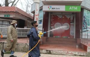 An employee of the Srinagar Municipal Corporation (SMC) spraying disinfectant on an ATM on Residency Road in Srinagar .(Waseem Andrabi) An employee of the Srinagar Municipal Corporation (SMC) spraying disinfectant on an ATM on Residency Road in Srinagar .(Waseem Andrabi)