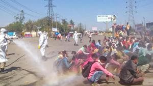 A screen grab shows healthcare workers, in protective suits, spray a solution through hose pipe on migrants before allowing them to enter the town of Bareilly, Monday, March 30, 2020. The migrants reached the town due to the nationwide complete lockdown imosed to limit the spread of coronavirus.(PTI)