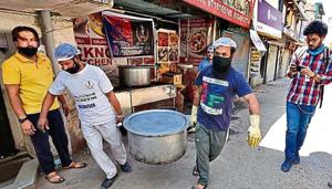 Volunteers carry a food container outside a community kitchen in Delhi’s Okhla area.(Burhaan Kinu/HT) Volunteers carry a food container outside a community kitchen in Delhi’s Okhla area.(Burhaan Kinu/HT)