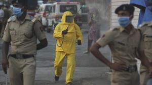 A civic worker sanitizes an area as policemen stand guard after a protest against the ongoing lockdown, at a slum in Mumbai, India, Tuesday, April 14, 2020.(AP photo) A civic worker sanitizes an area as policemen stand guard after a protest against the ongoing lockdown, at a slum in Mumbai, India, Tuesday, April 14, 2020.(AP photo)