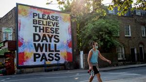 A pedestrian walks past a billboard reading "Please believe these days will pass" on Broadway Market in east London on April 24, 2020 as life continued in Britain under a lockdown designed to slow the transmission of the novel coronavirus.(AFP) A pedestrian walks past a billboard reading "Please believe these days will pass" on Broadway Market in east London on April 24, 2020 as life continued in Britain under a lockdown designed to slow the transmission of the novel coronavirus.(AFP)