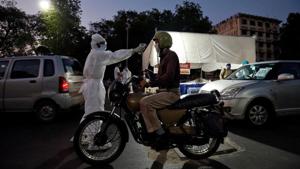 A health worker uses an infrared thermometer to measure the temperature of a motorcyclist on a road during a nationwide lockdown to slow the spreading of the coronavirus disease (COVID-19) in Ahmedabad.(REUTERS) A health worker uses an infrared thermometer to measure the temperature of a motorcyclist on a road during a nationwide lockdown to slow the spreading of the coronavirus disease (COVID-19) in Ahmedabad.(REUTERS)