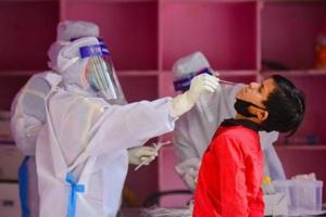 A medical worker takes a swab from a child during a Covid-19 testing drive.(HT Photo) A medical worker takes a swab from a child during a Covid-19 testing drive.(HT Photo)