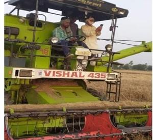 A postman providing money to a farmer reaping his crop on a combine machine in Hisar.(HT PHOTO)