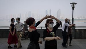 This photo taken on May 1, 2020 shows people wearing face masks as a precaution against the Covid-19 coronavirus as they dance under Wuhan Bridge in Wuhan, in China's central Hubei province.(AFP) This photo taken on May 1, 2020 shows people wearing face masks as a precaution against the Covid-19 coronavirus as they dance under Wuhan Bridge in Wuhan, in China's central Hubei province.(AFP)