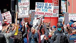 Angry protesters hold banners during a demonstration demanding the reopening of the US economy, in Chicago, Illinois. Angry protesters hold banners during a demonstration demanding the reopening of the US economy, in Chicago, Illinois.
