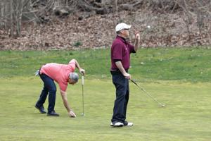One golfer places his ball on the green as another tosses his ball into the air before catching it.(AP) One golfer places his ball on the green as another tosses his ball into the air before catching it.(AP)