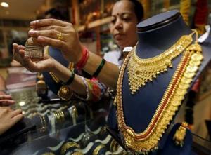 A salesperson shows a gold earring to customers at a jewellery showroom in Mumbai in this file photo.(Reuters Photo) A salesperson shows a gold earring to customers at a jewellery showroom in Mumbai in this file photo.(Reuters Photo)