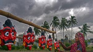 A woman dries clay demon masks on a roadside as dark clouds gather over the city ahead of landfall by Cyclone Amphan on the outskirt of Bhubaneswar, Odisha.(PTI) A woman dries clay demon masks on a roadside as dark clouds gather over the city ahead of landfall by Cyclone Amphan on the outskirt of Bhubaneswar, Odisha.(PTI)
