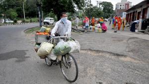A vegetable vendor pushes his cycle past migrant women filling containers with water a roadside tap during lockdown in Jammu, Jammu and Kashmir on Friday.(Nitin Kanotra /HT Photo) A vegetable vendor pushes his cycle past migrant women filling containers with water a roadside tap during lockdown in Jammu, Jammu and Kashmir on Friday.(Nitin Kanotra /HT Photo)
