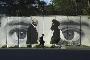 A young boy carries a sack of goods on his back as he walks past a wall depicting Washington's peace envoy Zalmay Khalilzad and Mullah Abdul Ghani Baradar, the leader of the Taliban delegation, Kabul, Afghanistan, Tuesday, May 4, 2020(AP) A young boy carries a sack of goods on his back as he walks past a wall depicting Washington's peace envoy Zalmay Khalilzad and Mullah Abdul Ghani Baradar, the leader of the Taliban delegation, Kabul, Afghanistan, Tuesday, May 4, 2020(AP)