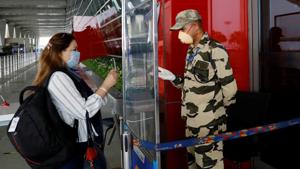 A Central Industrial Security Force personnel checks the identity card of a woman through a glass shield, ahead of the resumption of domestic flights from Monday.(Reuters Photo) A Central Industrial Security Force personnel checks the identity card of a woman through a glass shield, ahead of the resumption of domestic flights from Monday.(Reuters Photo)