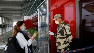 A member of the Central Industrial Security Force (CISF) checks the ID of a woman through a glass shield, after the government allowed domestic flight services to resume from Monday, at the Indira Gandhi International (IGI) Airport in New Delhi.(Reuters Photo) A member of the Central Industrial Security Force (CISF) checks the ID of a woman through a glass shield, after the government allowed domestic flight services to resume from Monday, at the Indira Gandhi International (IGI) Airport in New Delhi.(Reuters Photo)