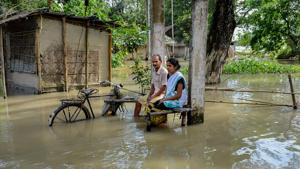 Villagers in the flood-hit locality of Solmara in Nalbari district of Assam on Thursday.(PTI PHOTO.)