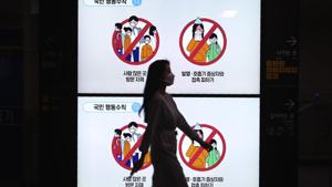 A woman wearing a face mask passes by screens showing the civil behavior rules against the new coronavirus at a subway station in Seoul, South Korea, Thursday, May 28, 2020. The sign reads: A woman wearing a face mask passes by screens showing the civil behavior rules against the new coronavirus at a subway station in Seoul, South Korea, Thursday, May 28, 2020. The sign reads: