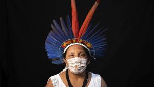 Sonia Vilacio, 46, of the Sateré Mawé indigenous ethnic group, poses for a portrait wearing the traditional dress of her tribe and a face mask amid the spread of the new coronavirus in Manaus, Brazil, Wednesday, May 27, 2020. The new coronavirus has hit Sônia Vilacio twice: when tourists disappeared from Manaus and she was left without an income from selling arts and crafts, and soon after when she fell ill with a fever, shortness of breath, and a cough, telltale signs of COVID-19. (AP Photo/Felipe Dana) (AP) Sonia Vilacio, 46, of the Sateré Mawé indigenous ethnic group, poses for a portrait wearing the traditional dress of her tribe and a face mask amid the spread of the new coronavirus in Manaus, Brazil, Wednesday, May 27, 2020. The new coronavirus has hit Sônia Vilacio twice: when tourists disappeared from Manaus and she was left without an income from selling arts and crafts, and soon after when she fell ill with a fever, shortness of breath, and a cough, telltale signs of COVID-19. (AP Photo/Felipe Dana) (AP)
