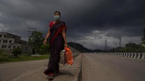 An Indian woman wearing a mask walks on a road as rain clouds hover over in Guwahati, India.(AP) An Indian woman wearing a mask walks on a road as rain clouds hover over in Guwahati, India.(AP)