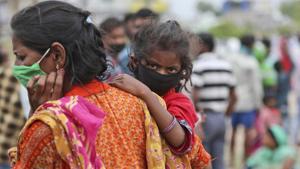 A woman carries a child as they wait with other migrant worker families to have their temperatures checked before being allowed to board a train tomorrow for their hometowns.(AP) A woman carries a child as they wait with other migrant worker families to have their temperatures checked before being allowed to board a train tomorrow for their hometowns.(AP)