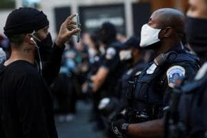 A demonstrator holds a mobile phone as he faces police officers near Black Lives Matter Plaza as racial inequality protests continue, Washington, June 23, 2020(REUTERS)