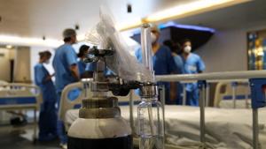 Doctor gather near to an oxygen cylinder in a ward makeshift ward at an emergency Covid-19 care center set up in the Shehnai Banquet Hall at the Lok Nayak Jai Prakash Hospital Annexe in New Delhi on Wednesday.(Bloomberg Photo) Doctor gather near to an oxygen cylinder in a ward makeshift ward at an emergency Covid-19 care center set up in the Shehnai Banquet Hall at the Lok Nayak Jai Prakash Hospital Annexe in New Delhi on Wednesday.(Bloomberg Photo)