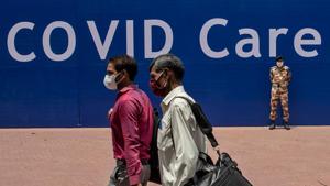 Workers walk past an Indo-Tibetan Border Police (ITBP) officer at the campus of Radha Soami Satsang Beas, a spiritual organization, where a coronavirus disease care centre has been constructed for the patients amidst the spread of the disease, in New Delhi.(REUTERS) Workers walk past an Indo-Tibetan Border Police (ITBP) officer at the campus of Radha Soami Satsang Beas, a spiritual organization, where a coronavirus disease care centre has been constructed for the patients amidst the spread of the disease, in New Delhi.(REUTERS)