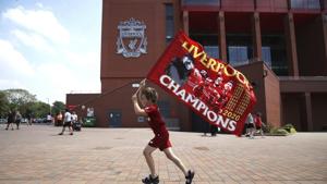 Liverpool fan Dillon Parry waves a flag outside Anfield in Liverpool, England, Friday June 26, 2020. Liverpool clinched its first league title since 1990 on Thursday, ending an agonizing title drought.(AP) Liverpool fan Dillon Parry waves a flag outside Anfield in Liverpool, England, Friday June 26, 2020. Liverpool clinched its first league title since 1990 on Thursday, ending an agonizing title drought.(AP)