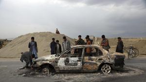 FILE - In this April 9, 2019, file photo, Afghans watch a civilian vehicle burnt after being shot by US forces following an attack near the Bagram Air Base, north of Kabul, Afghanistan.(AP)