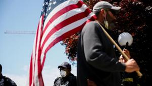 A man holding an American flag walks by Seattle Police officers guarding a closed Cal Anderson Park in the former Capitol Hill Occupied Protest (CHOP) area on the Fourth of July holiday in Seattle, Washington, U.S. July 4, 2020.(Reuters photo) A man holding an American flag walks by Seattle Police officers guarding a closed Cal Anderson Park in the former Capitol Hill Occupied Protest (CHOP) area on the Fourth of July holiday in Seattle, Washington, U.S. July 4, 2020.(Reuters photo)