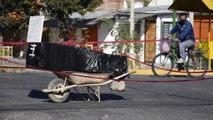 A coffin wrapped in plastic holding the remains of an unidentified men, who died last week, sits on a wheelbarrow in the middle of a street, placed there by his family to draw attention of the authorities to show that his remains are yet to be collected, in Cochabamba, Bolivia on Saturday.(AP File Photo) A coffin wrapped in plastic holding the remains of an unidentified men, who died last week, sits on a wheelbarrow in the middle of a street, placed there by his family to draw attention of the authorities to show that his remains are yet to be collected, in Cochabamba, Bolivia on Saturday.(AP File Photo)