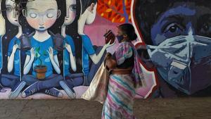 A woman wearing a protective mask walks past a graffiti during an extended nationwide lockdown to slow the spreading of coronavirus disease (COVID-19) in Mumbai.(REUTERS) A woman wearing a protective mask walks past a graffiti during an extended nationwide lockdown to slow the spreading of coronavirus disease (COVID-19) in Mumbai.(REUTERS)
