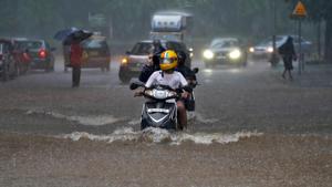 People ride their scooters through a water-logged road during heavy rains in Mumbai, India.(REUTERS) People ride their scooters through a water-logged road during heavy rains in Mumbai, India.(REUTERS)