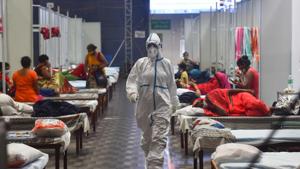 A health worker in PPE walks past Covid-19 patient housed inside the Commonwealth Games Village Sports Complex which is temporarily converted into a coronavirus care centre at Patparganj in New Delhi on Tuesday.(Sanchit Khanna/HT Photo) A health worker in PPE walks past Covid-19 patient housed inside the Commonwealth Games Village Sports Complex which is temporarily converted into a coronavirus care centre at Patparganj in New Delhi on Tuesday.(Sanchit Khanna/HT Photo)