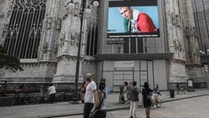 Pedestrians pass by a screen on the Duomo cathedral, showing a Moschino model during the Milan Digital Fashion Week, in Milan, Italy, Tuesday, July 14, 2020.(AP Photo/Luca Bruno) Pedestrians pass by a screen on the Duomo cathedral, showing a Moschino model during the Milan Digital Fashion Week, in Milan, Italy, Tuesday, July 14, 2020.(AP Photo/Luca Bruno)