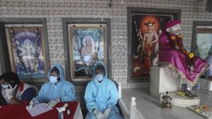 Health workers wait to screen people for Covid-19 symptoms at a temple in Mumbai, India.(AP) Health workers wait to screen people for Covid-19 symptoms at a temple in Mumbai, India.(AP)