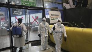 A health worker sanitizes the doorway as doctors come out from a Covid-19 care centre functioning in an indoor stadium in New Delhi on Monday.(AP Photo) A health worker sanitizes the doorway as doctors come out from a Covid-19 care centre functioning in an indoor stadium in New Delhi on Monday.(AP Photo)