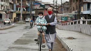 A man wearing face mask pulls his bicycle on a deserted road in Srinagar on Tuesday.(ANI Photo) A man wearing face mask pulls his bicycle on a deserted road in Srinagar on Tuesday.(ANI Photo)