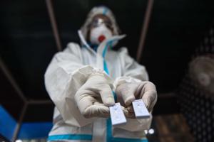 A health worker wearing PPE coveralls holds out Rapid Antigen test kits before preparing to collect swab samples to test for coronavirus, near Minto Bridge in New Delhi.(Sanchit Khanna/HT PHOTO) A health worker wearing PPE coveralls holds out Rapid Antigen test kits before preparing to collect swab samples to test for coronavirus, near Minto Bridge in New Delhi.(Sanchit Khanna/HT PHOTO)