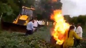 The incident came to light after a video went viral on social media in which the woman is seen setting herself ablaze in front of a team of government personnel while a JCB machine is seen destroying the crop in her farm field. (Videograb) The incident came to light after a video went viral on social media in which the woman is seen setting herself ablaze in front of a team of government personnel while a JCB machine is seen destroying the crop in her farm field. (Videograb)