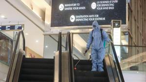 A man in personal protective equipment (PPE) sprays disinfectant on an escalator inside a mall in Mumbai.(Reuters Photo) A man in personal protective equipment (PPE) sprays disinfectant on an escalator inside a mall in Mumbai.(Reuters Photo)