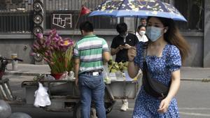 A woman wearing a mask to curb the spread of the coronavirus walks past a street vendor selling lotus flowers and seeds in Beijing on Frida.(AP) A woman wearing a mask to curb the spread of the coronavirus walks past a street vendor selling lotus flowers and seeds in Beijing on Frida.(AP)