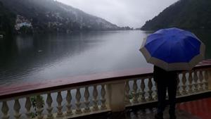 A local person walking past Naini Lake in Nainital district on Sunday amid heavy rain.(RAAJIV KALA/HT PHOTO.) A local person walking past Naini Lake in Nainital district on Sunday amid heavy rain.(RAAJIV KALA/HT PHOTO.)