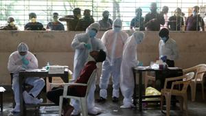 A health worker in personal protective equipment (PPE) collects a swab sample from a man as people outside wait for their test results during a rapid antigen testing check up campaign for the coronavirus disease at a school in Mumbai.(REUTERS) A health worker in personal protective equipment (PPE) collects a swab sample from a man as people outside wait for their test results during a rapid antigen testing check up campaign for the coronavirus disease at a school in Mumbai.(REUTERS)