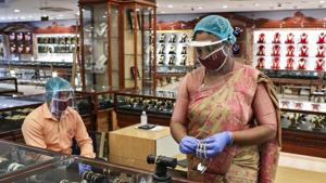 A sales woman wearing a face shield and a mask arranges gold bangles at a jewellery showroom in Kolkata in this file photo.(REUTERS) A sales woman wearing a face shield and a mask arranges gold bangles at a jewellery showroom in Kolkata in this file photo.(REUTERS)